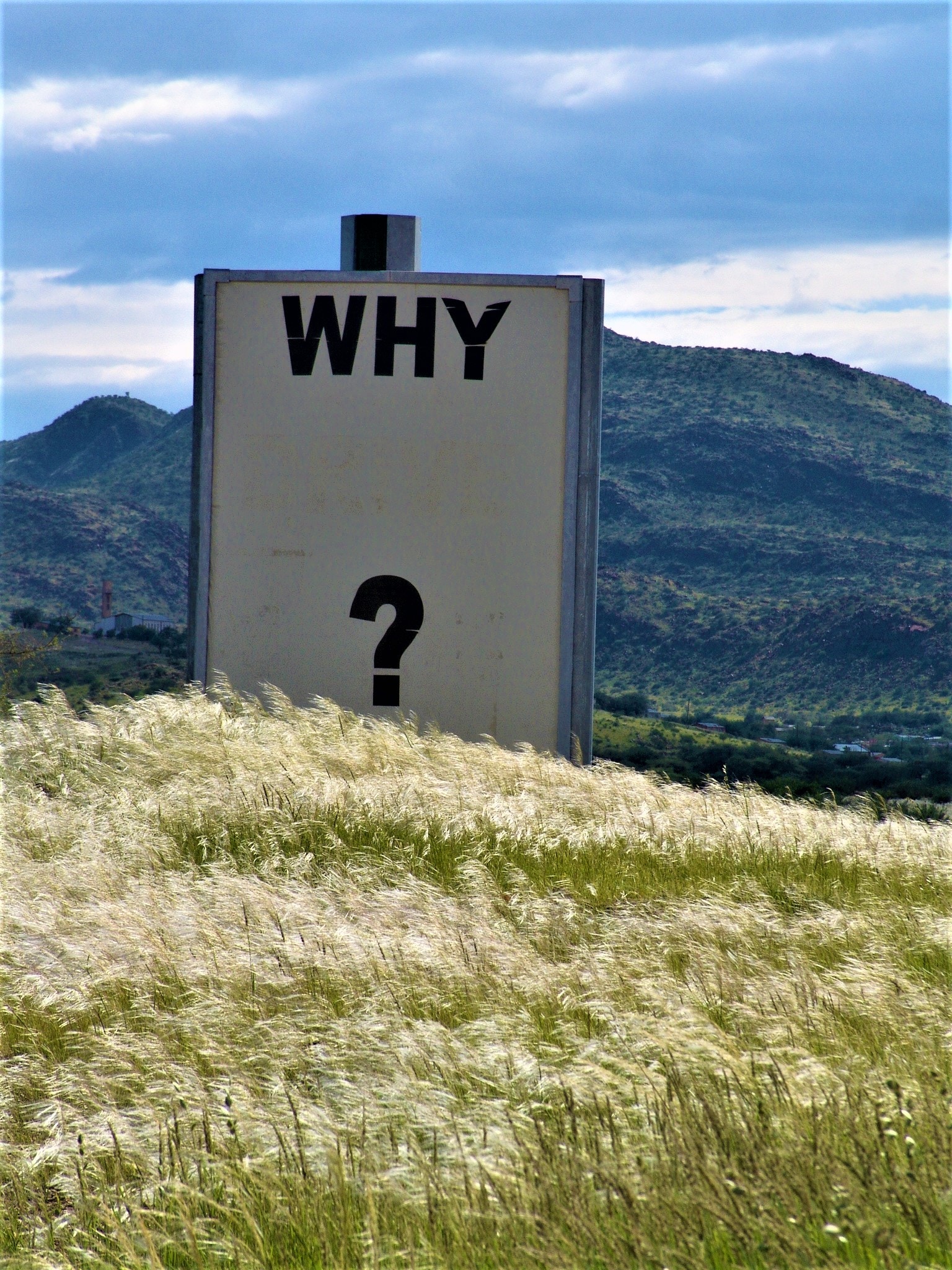 a sign asking the question, mountain and sky behind it