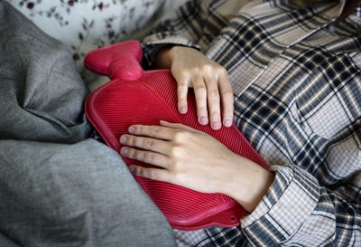 woman holding hot water bottle to her stomach