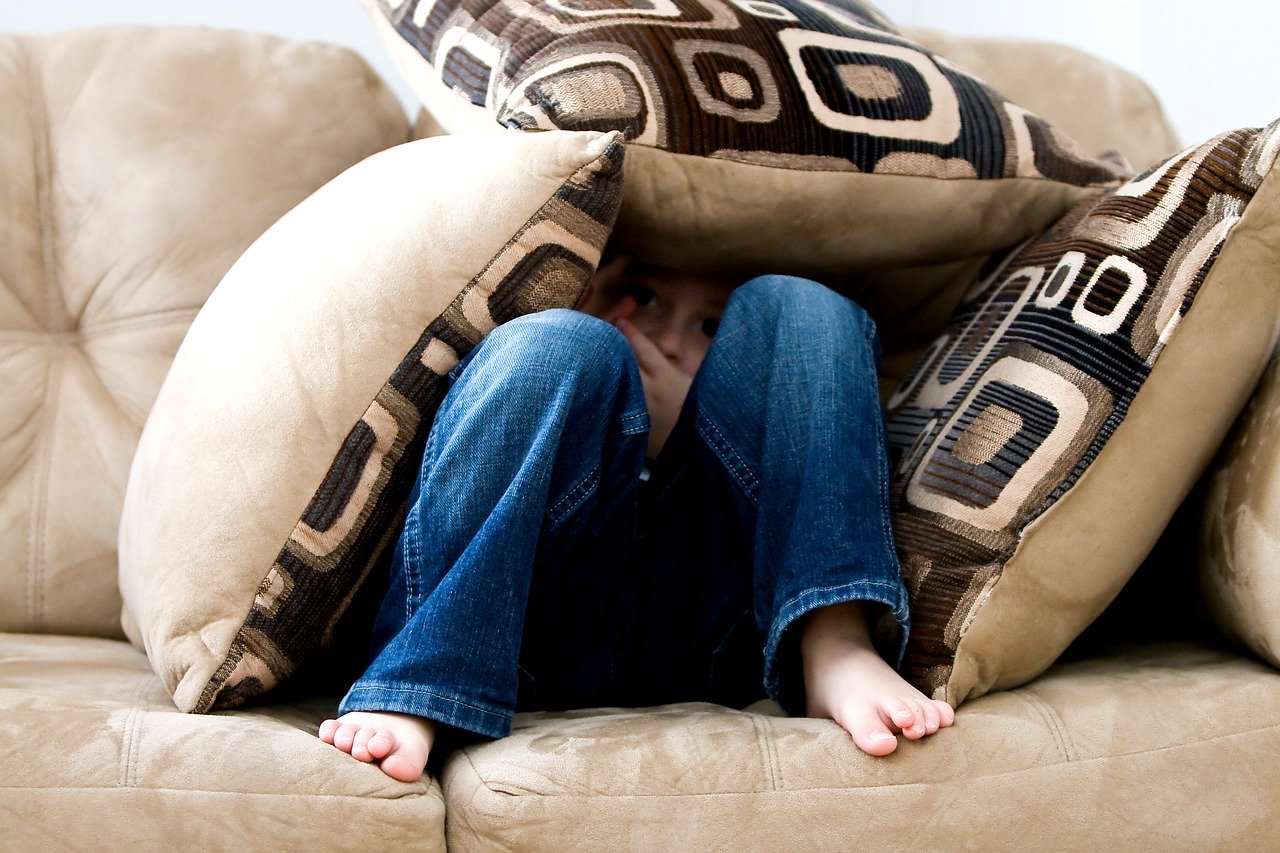 boy hiding under pillows